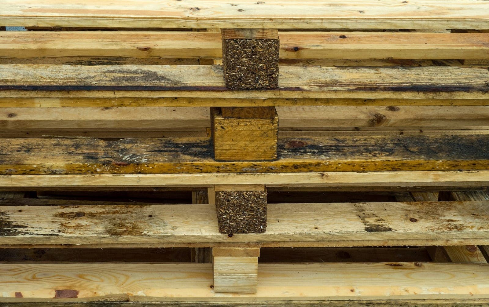 Pile de palettes en bois usagées empilées en extérieur : le bois de récupération le plus courant, et celui dont le marquage décide s'il peut brûler ou non